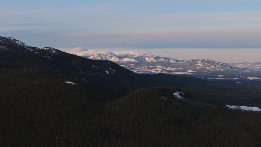 Stunning aerial view of Fish Lake’s frozen expanse surrounded by snow-covered mountains near Whitehorse, Yukon. A pristine winter landscape showcasing the beauty of Canada’s wilderness