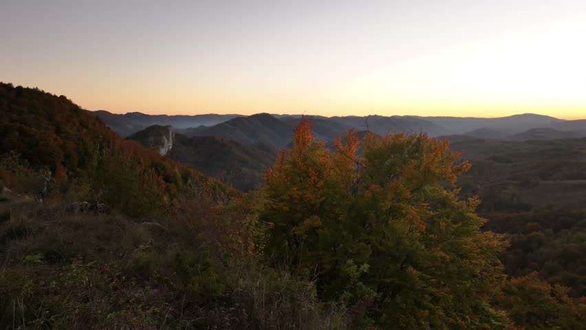 Experience the magic of the Apuseni Mountains at sunset, with golden hour light illuminating the rugged peaks and valleys, captured in this stunning aerial footage.