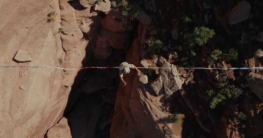 Top down aerial view of man on highline slackline over desert canyon