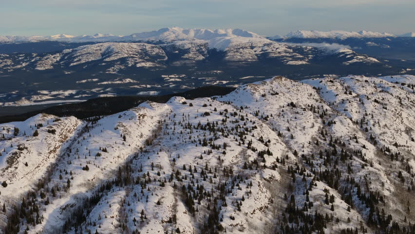 A dramatic aerial view of Fish Lake’s icy expanse in Whitehorse, Yukon. Snow-draped mountains and a serene frozen landscape define Canada’s breathtaking northern beauty