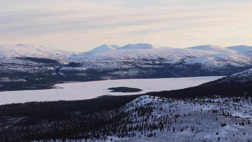 Discover the frozen beauty of Fish Lake at sunset, near Whitehorse, Yukon. Aerial views capture the serene, icy landscapes in the heart of Canada’s rugged winter wilderness.