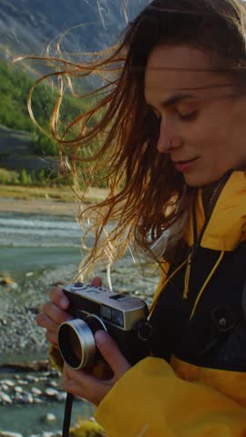 Female photographer taking pictures with vintage camera of a stunning river landscape under vibrant skies