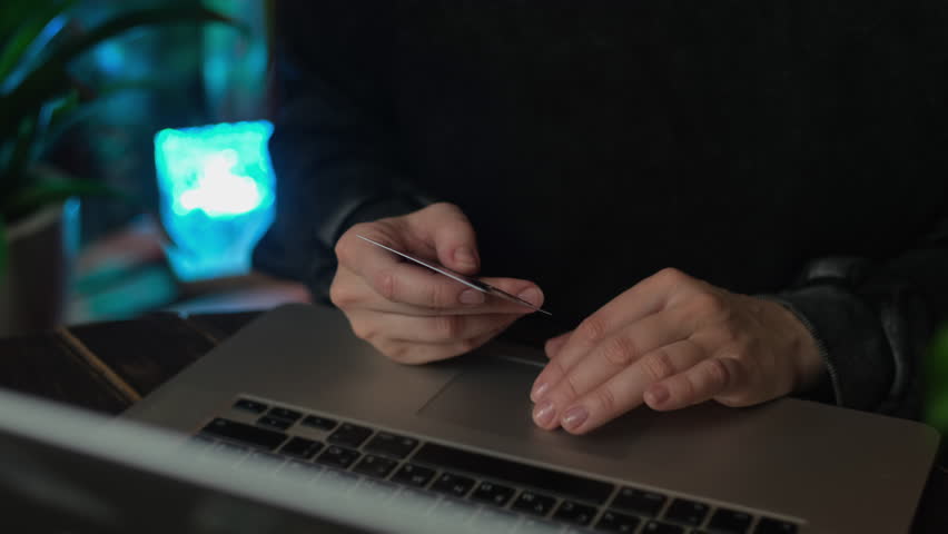 Online payments, money transfer online. Woman with bank card in her hands uses laptop to pay for online orders