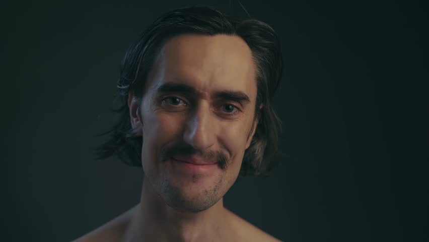 Joyful Man Adjusting Mustache Young European man laughs joyfully with tears while adjusting his mustache in a cinematic setting