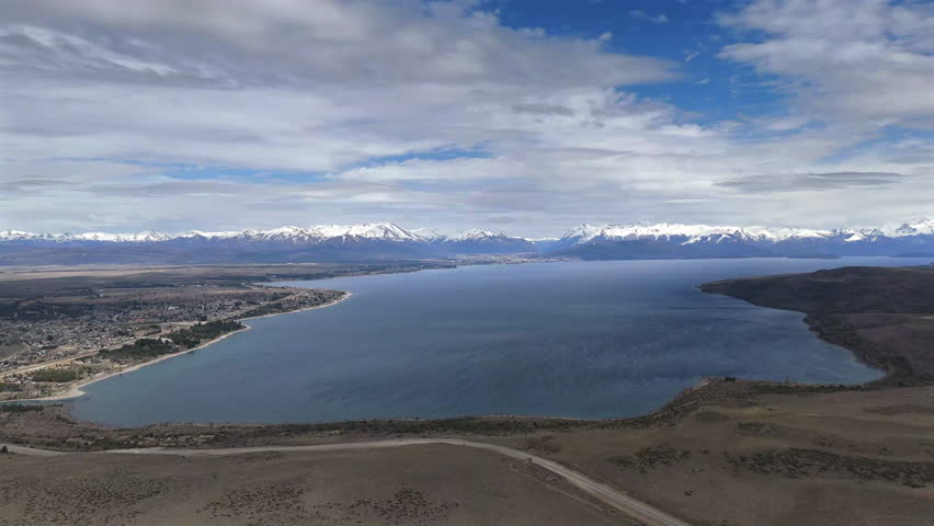 Aerial view of Lake Nahuel Huapi and the town of Dina Huapi, with the surrounding mountains on a partly cloudy day, in the Argentinean Patagonia.