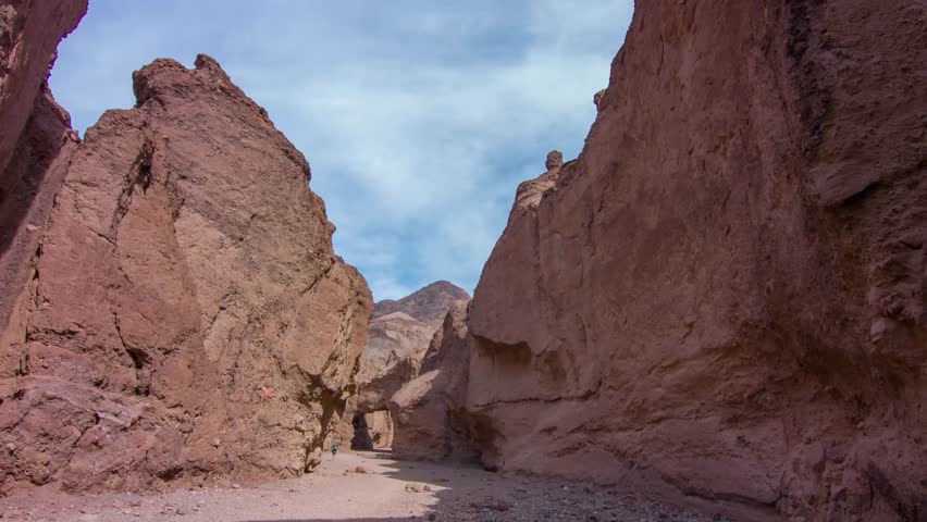 Join the adventure of hiking between big rocks, lit by golden sunlight, at the Natural Bridge Trail in Death Valley National Park, California, USA.
