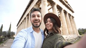 Happy couple in love visiting the Acropolis of Athens, Greece - Smiling  boyfriend and girlfriend taking selfie video with smart phone mobile on weekend vacation - Travelling and technology concept  - Powered by Shutterstock - Get 15% off with code: PIKWIZARD15