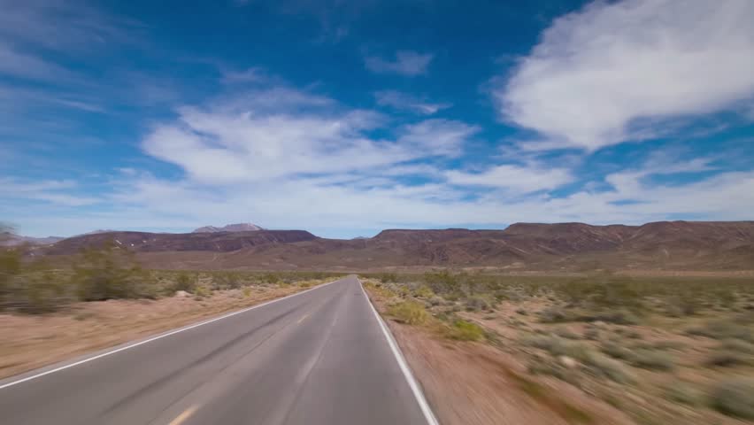 A scenic stretch of Canyon Road in Death Valley National Park, California, framed by towering mountain ranges and vast desert plains, ideal for travel footage and desert exploration enthusiasts.