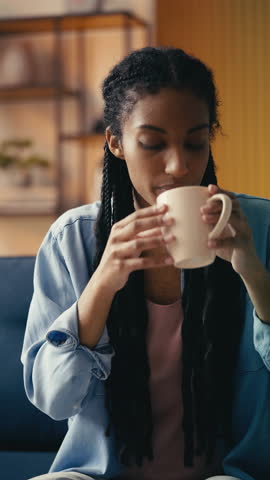 Young African American female takes a painkiller pill with water, feeling unwell