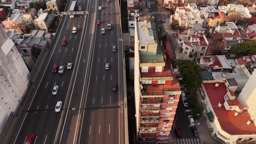 Traffic scene on Highway of Buenos Aires. Residential apartment blocks and towers during sunrise in the morning. Aerial top down shot. Loud suburb neighborhood in Argentina.