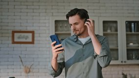 Cooking man looking smartphone turning music in cuisine closeup. Happy guy listening song in headphones enjoying at home kitchen. Smiling brunette in earphones preparing salad for breakfast alone  - Powered by Shutterstock - Get 15% off with code: PIKWIZARD15