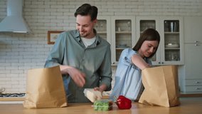 Couple arrived from grocery store putting shoppings kitchen countertop closeup. Smiling family unpacking eco paper packages at home cuisine. Delighted pair sorting food preparing for cooking dinner  - Powered by Shutterstock - Get 15% off with code: PIKWIZARD15