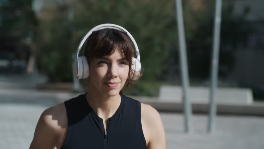 Video of sporty woman listening to music with headphones while running through the city