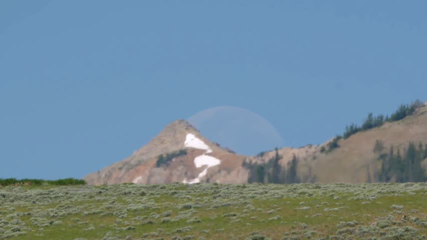 Faded moon behind a snowy hill in Yellowstone National Park, Wyoming, USA.
