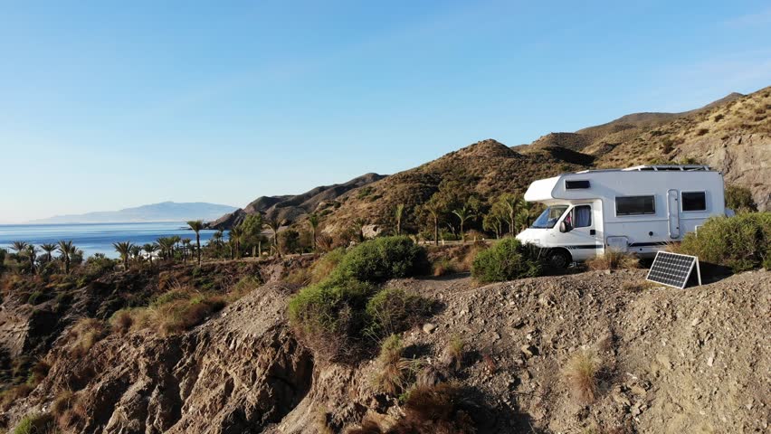Aerial view. Camper rv camping on cliff sea shore. Portable solar photovoltaic panel next to caravan. Mediterranean region of Villaricos, Almeria, eastern Andalusia, Spain.