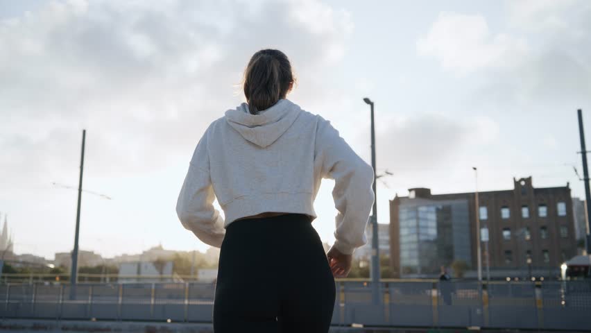 Video of sporty woman listening to music with headphones while running through the city