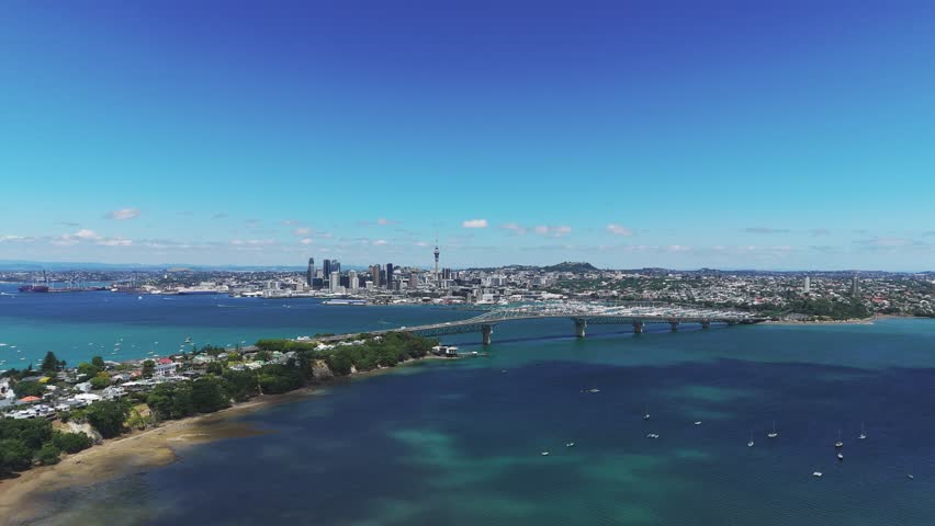 Auckland’s Waitemata Harbour, featuring Harbour Bridge, marina, and downtown skyline in vibrant daylight, aerial establish