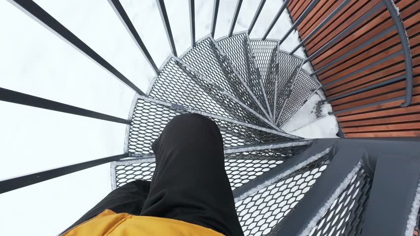 This captivating view features a beautifully designed spiral staircase with a textured metallic surface, elegantly surrounded by fresh snow, creating a striking contrast outdoors