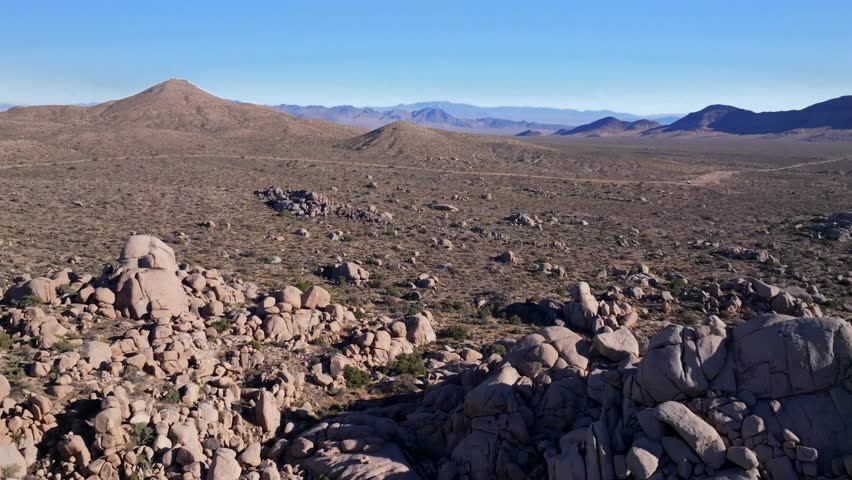 Drive road Kelso Pinto Basin Dunes Joshua Tree National Park California aerial drone Yucca Trees San Fernando County Mojave Colorado desert sunny afternoon blue sky rugged hill rock formation forward