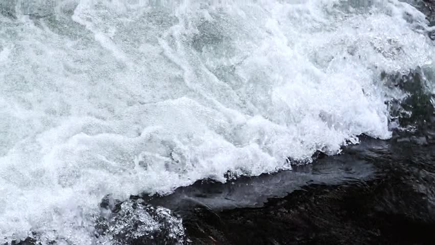 Fast stream of river water with dark bottom at site of small drop, creating white vast area filled with air bubbles, micro waterfall that favorable living conditions for living in this ecosystem