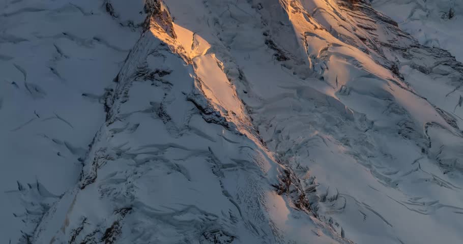 A breathtaking aerial view of a snow-capped mountain bathed in the warm glow of sunrise. Perfect for projects related to nature, adventure, and travel. Mount Baker view from airplane, Washington, USA