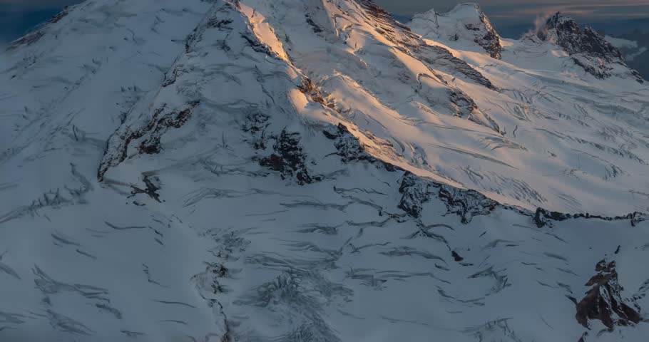 Aerial footage of Mountain during a breathtaking golden hour sunrise. Mount Baker view from airplane, Washington, USA. Snow, serene, awe-inspiring.