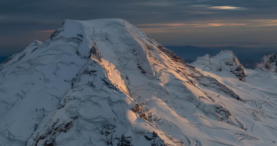 Stunning aerial view of a snow-capped mountain peak at sunset. A breathtaking winter wonderland landscape. Mount Baker view from airplane, Washington, USA