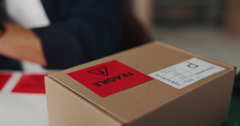 Box, sticker and ecommerce order in workshop with information for delivery, shipping or courier. Supply chain, package and small business with fragile label on cardboard parcel for cargo service.