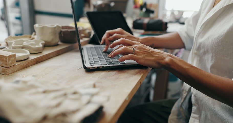 Woman, hands and typing with laptop for online order, communication or inventory at ceramic store. Closeup, female person or artisan writing with computer for art, craft or pottery at clay workshop