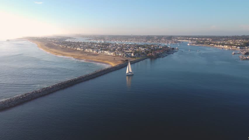 Balboa Peninsula Pan Past - Jetty Canal, Port Harbor Bay Entrance - to Newport Beach, Orange County, Southern California Coast, USA. Corona Del Mar. Mountian View City Skyline on Hillside