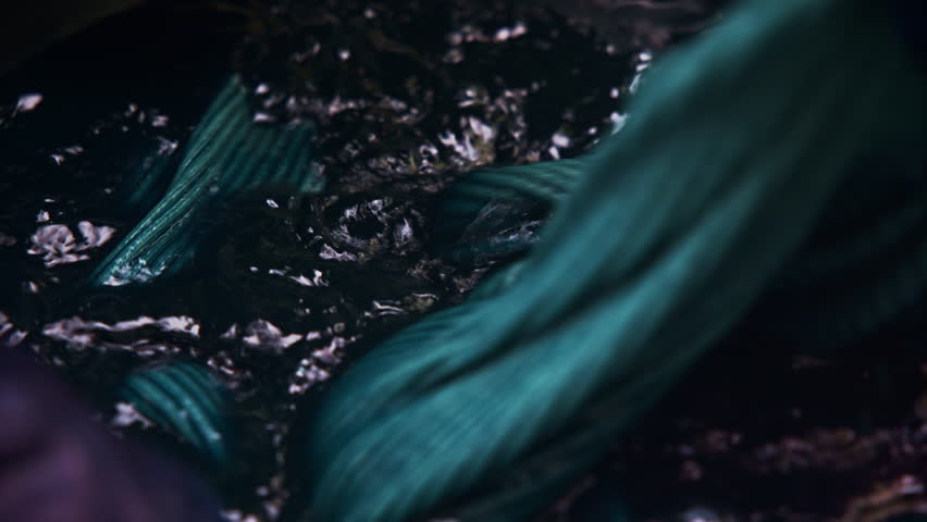 Cloth is carefully dipped and mixed in an indigo vat dye, creating a deep, rich color as it absorbs the dye for a vibrant finish