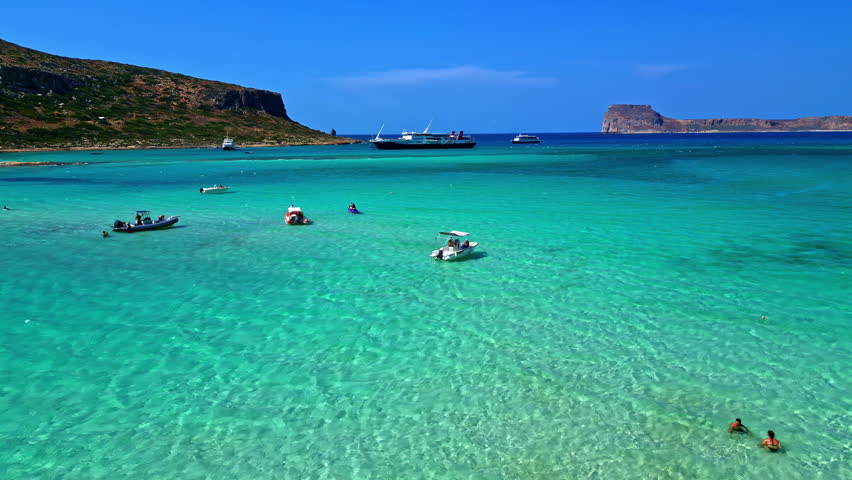Clear waters with small boats at Afrata Beach, surrounded by coastline in Crete, Greece