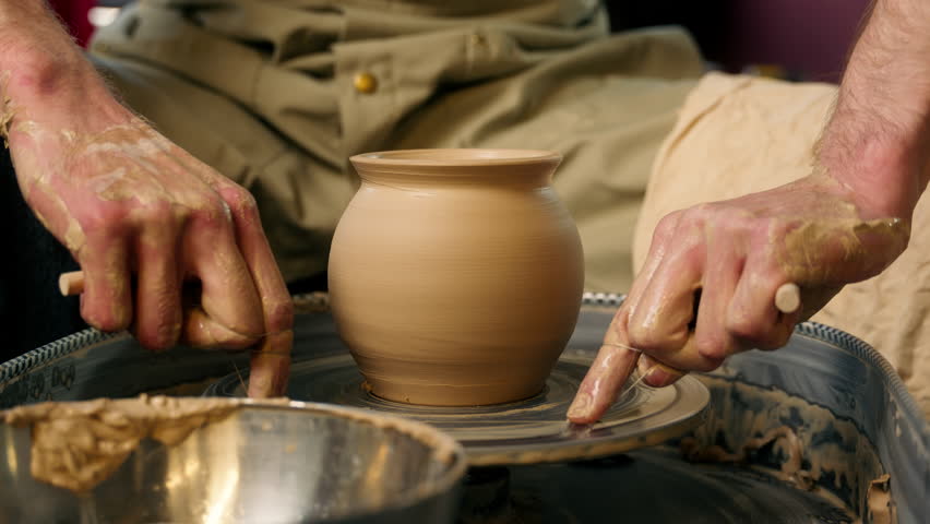 Master hands apron holding thread potter clay craft artisan man craftsman cutting wet vessel pottery wheel completed vase workshop finished pot handmade ceramics male manufacturing work process studio