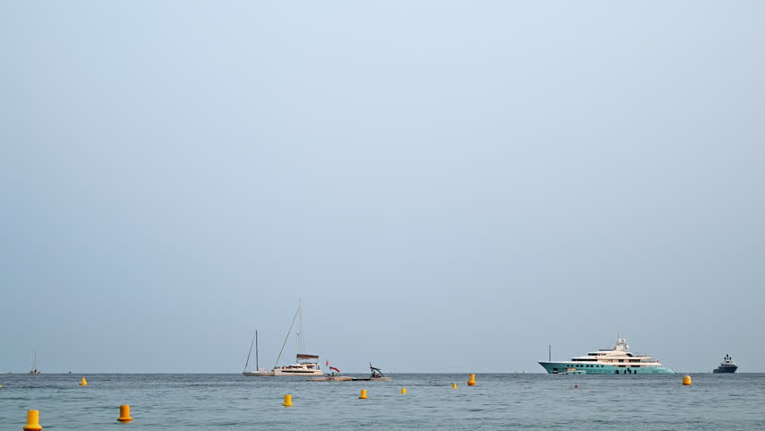 Mediterranean sea coast with floating yachts and boats at sunset in Cannes, France