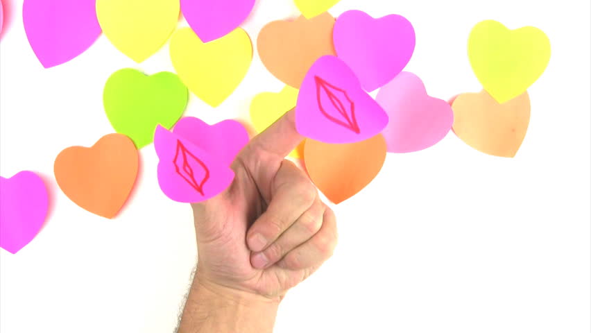 Man's hand with paper labels in the form of hearts on the thumb and forefinger