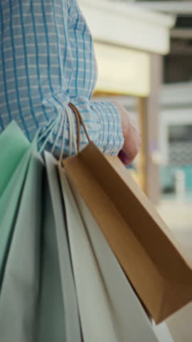 In a busy shopping mall, a man carries several bags filled with purchases. A young modern girl in a shopping mall carries bags with purchases of clothes in a good mood and with a confident gait