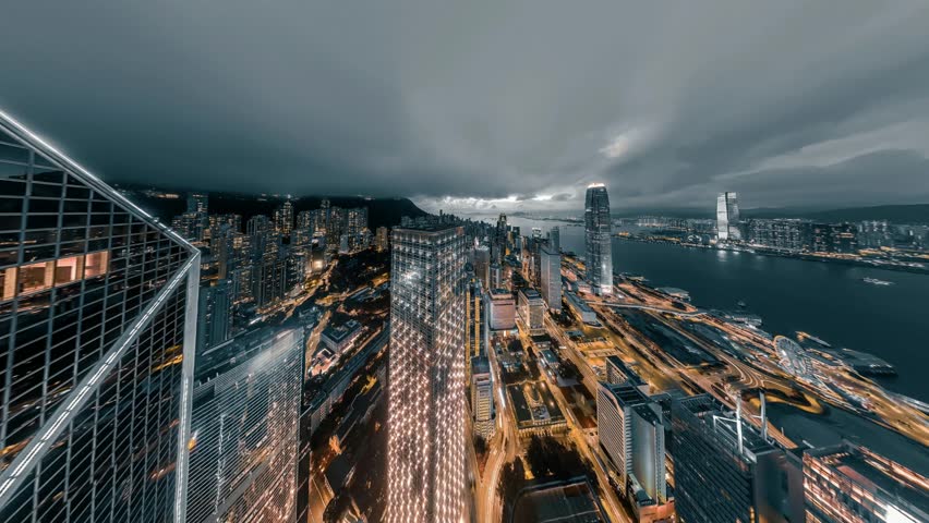 A stunning 4K still video captures a breathtaking panoramic view of Hong Kong's central district at night. The camera pans upwards, showcasing the city's vibrant skyline and illuminated skyscrapers ag