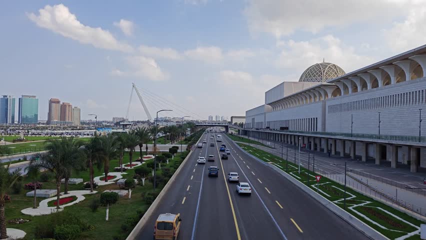 Wide shot of traffic on the Algiers highway passing the Great Mosque of Algiers with the cityscape in the background. Algiers.
