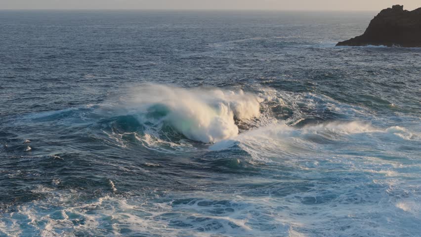 Huge power ocean wave crashing over sunset sky background. Slow motion of stormy ocean surf splashing on the coast of Madeira, Porto Moniz
