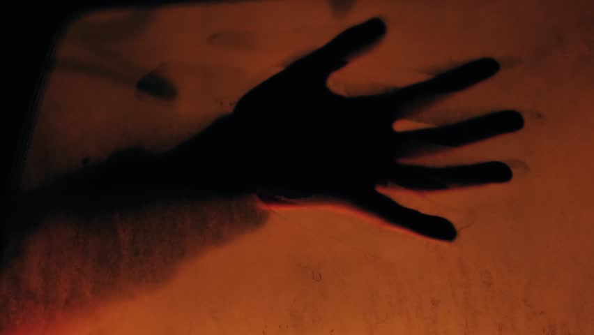 Tense shot of a hand silhouette pressing against a glowing car window, evoking despair and finality