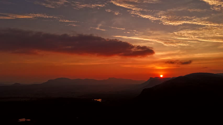 A stunning aerial view of a vibrant sunset over a vast mountain range, captured by a drone