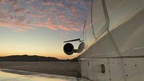 External right side view of a white color fuselage jet at the parking stand under some fluffy pink stratus clouds at sunrise. 4K - Powered by Shutterstock - Get 15% off with code: PIKWIZARD15