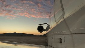 External right side view of a white color fuselage jet at the parking stand under some fluffy pink stratus clouds at sunrise. 4K - Powered by Shutterstock - Get 15% off with code: PIKWIZARD15