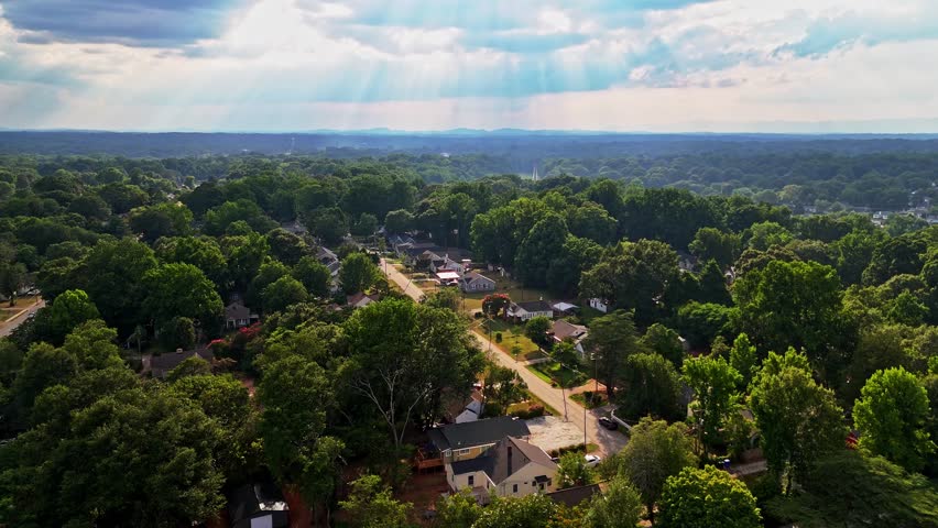 A drone fly-over of Greenville County in South Carolina showing a landscape of trees, mountains, and storm clouds.