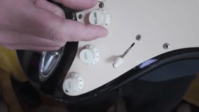 Close up of a musician's hand turning the volume knob on an electric guitar, setting the perfect sound - Powered by Shutterstock - Get 15% off with code: PIKWIZARD15