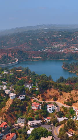 Residential Area near the Hollywood Reservoir. Hollywood Hills looking down on some beautiful houses on hillside in Los Angeles. Aerial view. Vertical video.