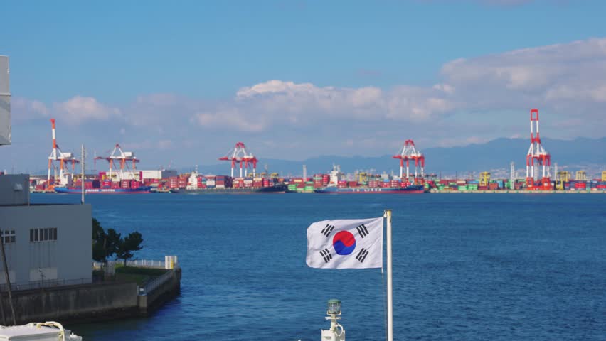 South Korea Flag Flying over Ocean with Shipping Cargo and Port in Background