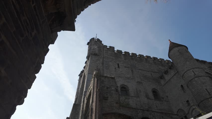 Medieval architecture of the Gravensteen castle in Ghent, Belgium, rising majestically against a clear blue sky
