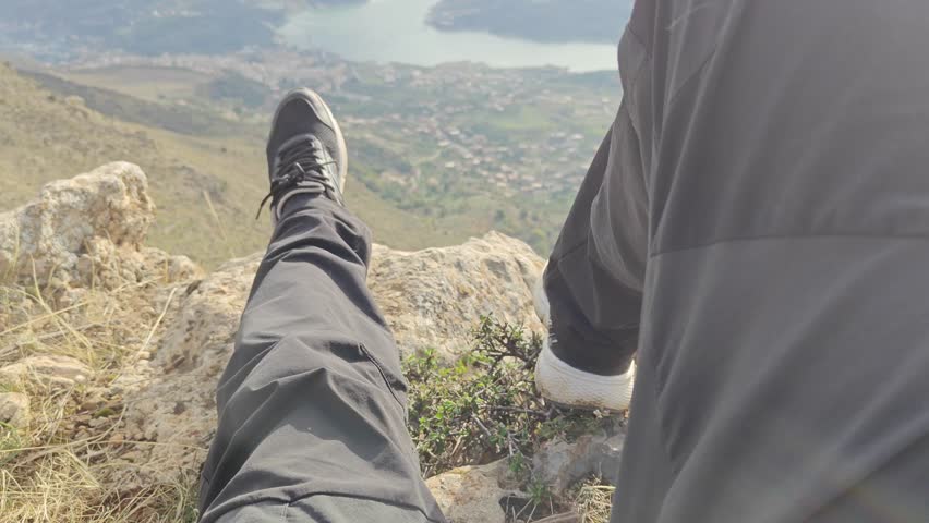 Low section of a man lying on the Adrar Kherrata peak, enjoying a panoramic view. Bejaia. Algeria