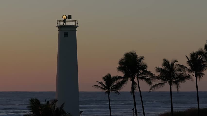 A serene sunset on Oahu Island, Hawaii, featuring a white lighthouse, calm ocean, gradient sky, and gently swaying palm trees in the foreground.